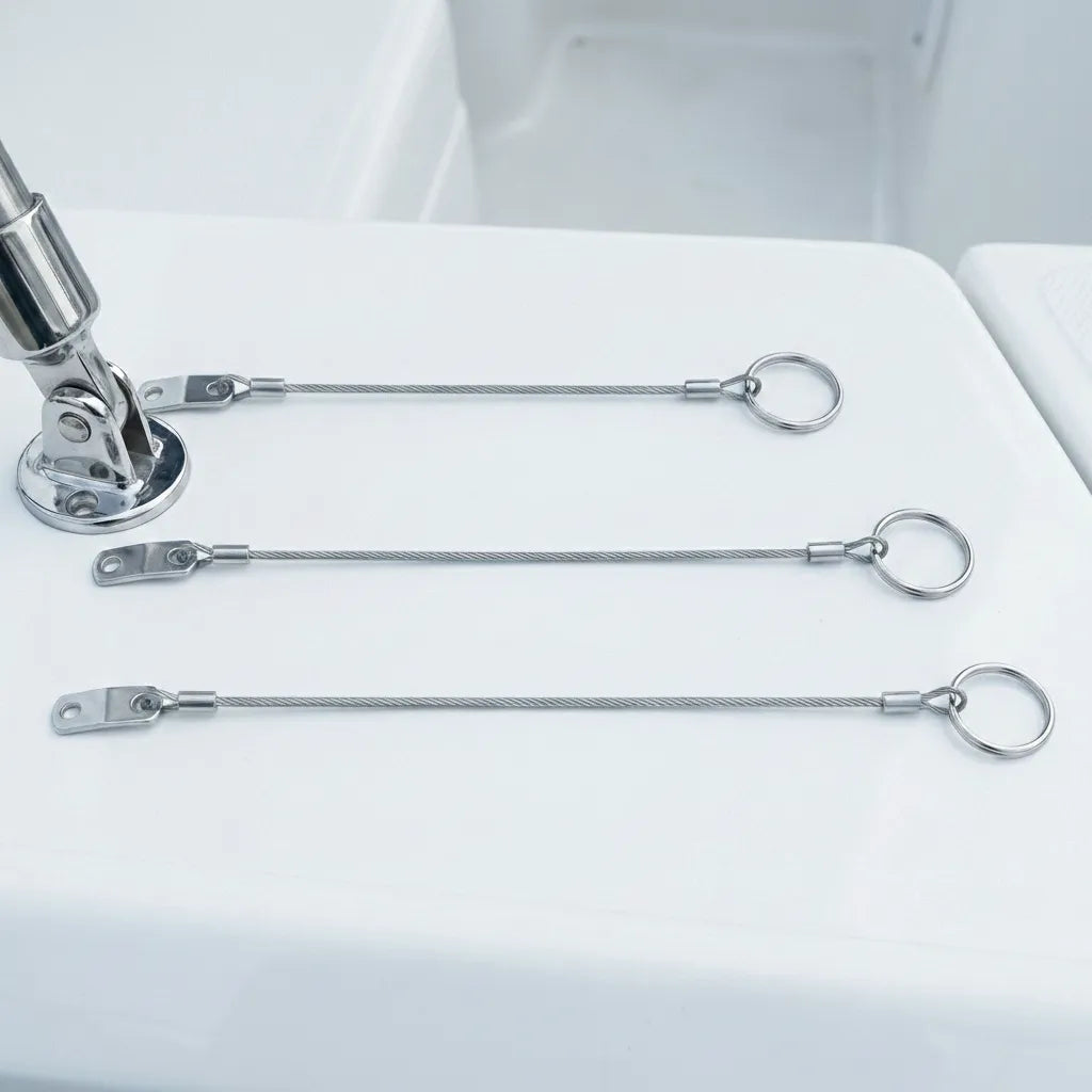 Marine safety tethers installed on a white fiberglass boat deck hinge to prevent quick-release pin loss.